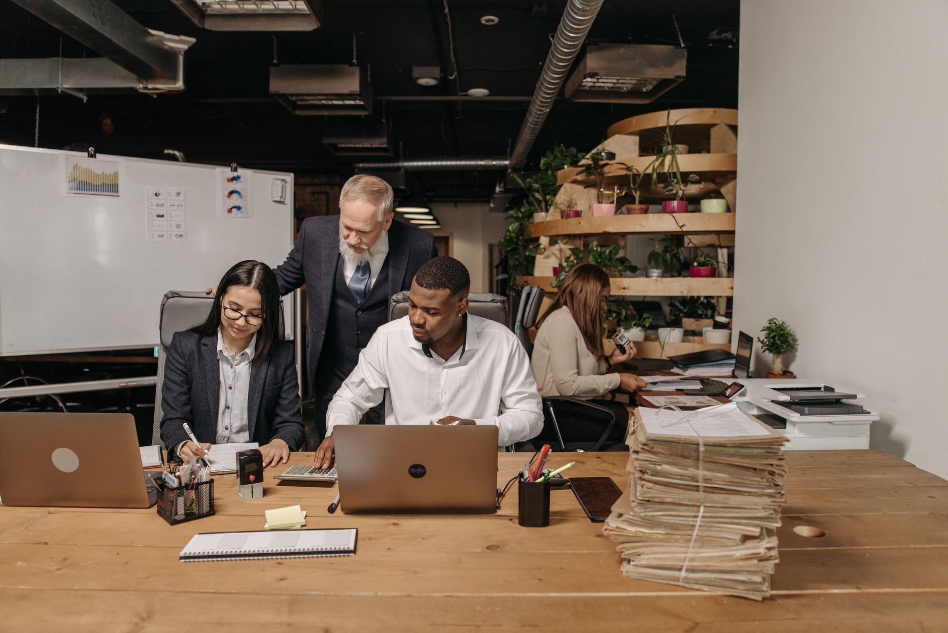 Team of professionals working collaboratively in a modern office environment with documents and laptops, illustrating The Security Questionnaire Process: Owners, Workflow, Submission Package and Trust Center