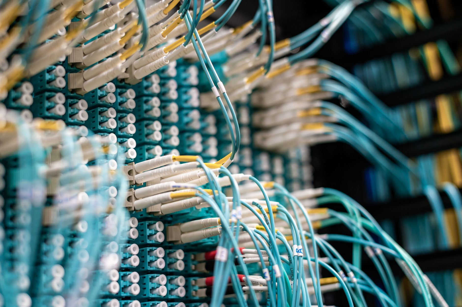 From below of long thin blue cables connected to row of small white connectors on system block in data center, illustrating Vanta and Drata for On-Prem SOC 2: What the Platform Automates and Who Collects the Rest
